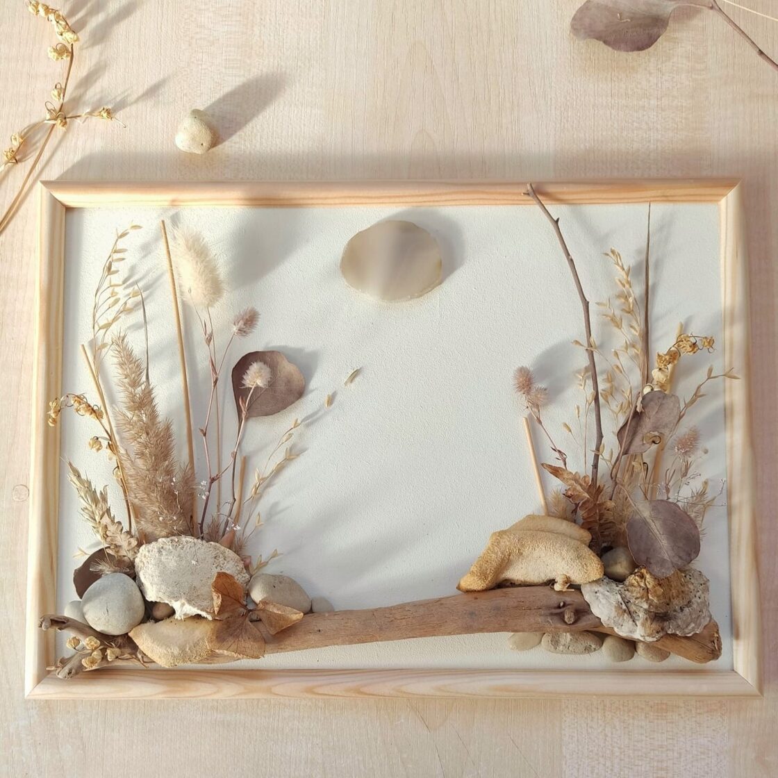 Nature-based wall artwork made from driftwood, dried plants and natural materials arranged on a painted surface